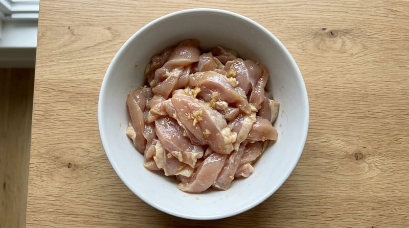 Sliced chicken thigh in a bowl, glossy from the velvet marinade
